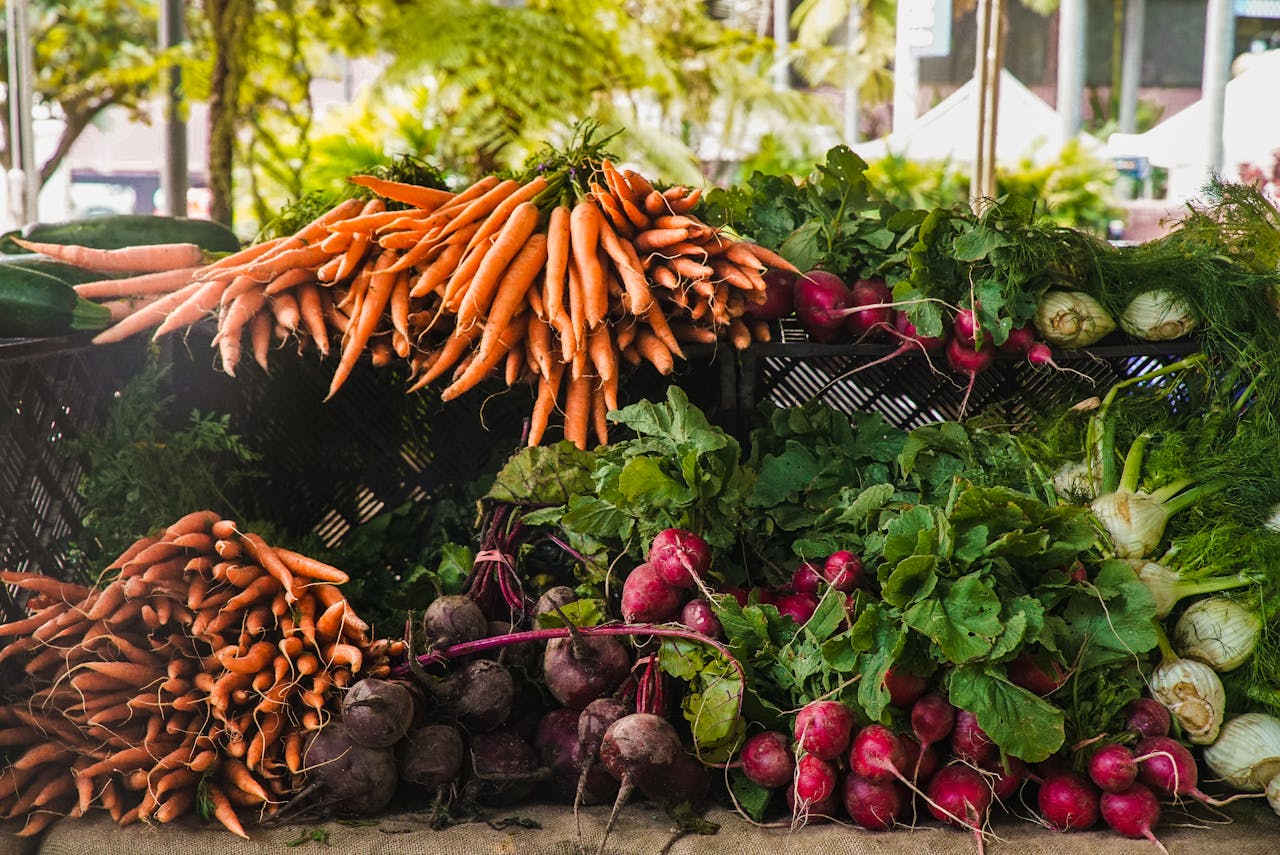 about-us A vibrant display of fresh carrots, radishes, and greens at a local outdoor market.